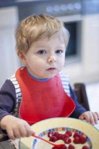 Portrait of cute toddler boy eating  fruit in a bowl