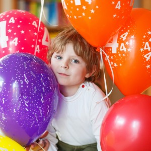 Happy little boy celebrating his 4 birthday with colorful balloons